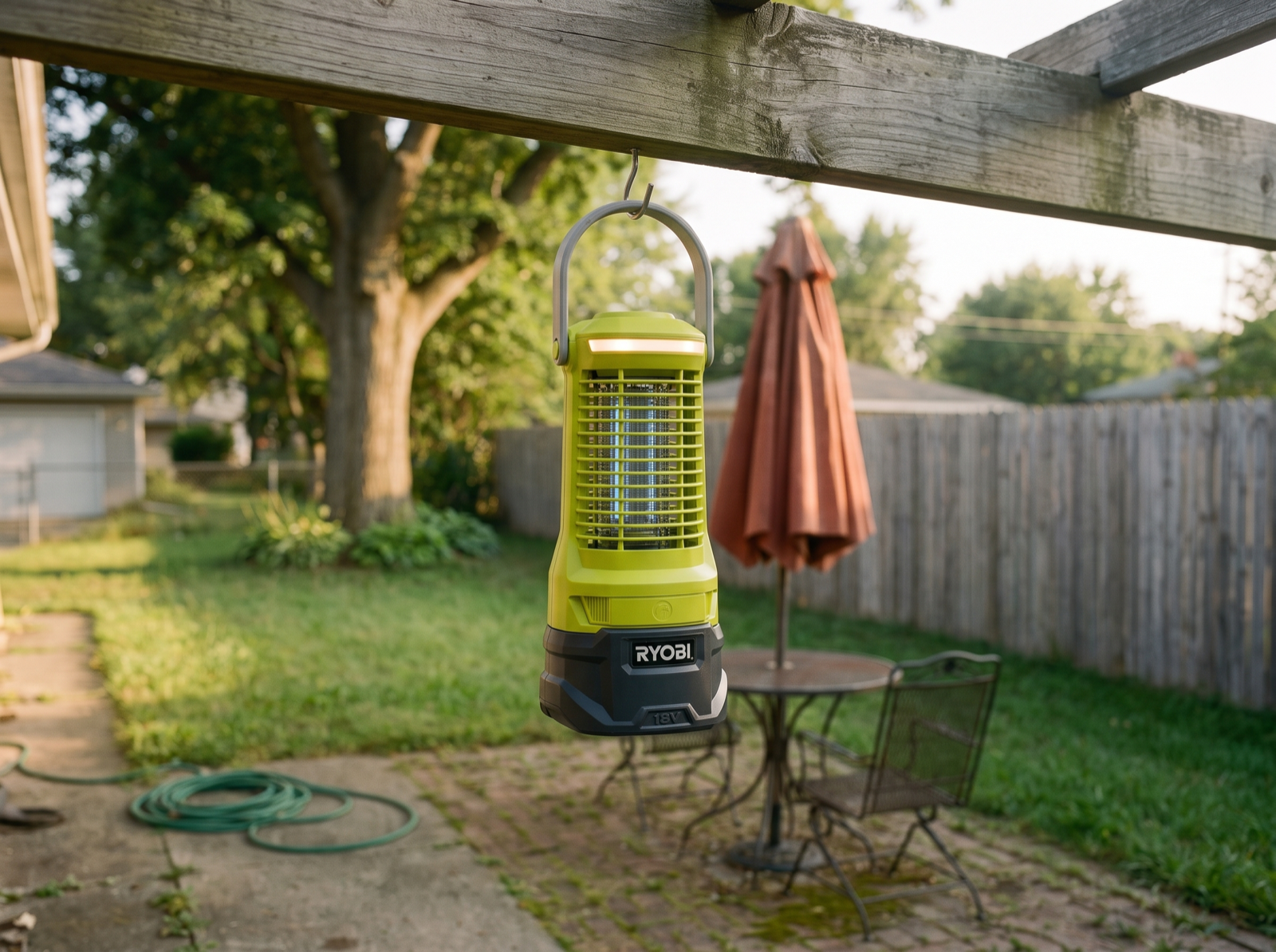A RYOBI 18V ONE+ bug zapper lantern hanging by its handle from a timber pergola beam above the patio, late afternoon.